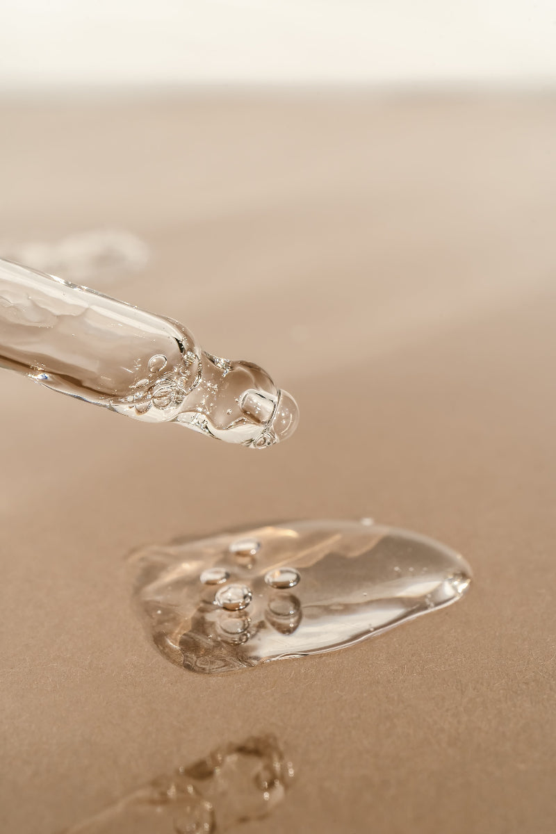 Close-up of a droplet of clear liquid on a beige surface
