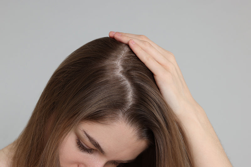 Woman with hand on head against a gray background